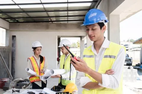 An electrical engineer stands with his arms crossed and holds a walkie-talkie Stock Photos
