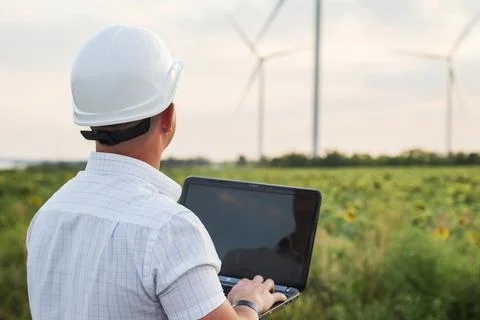 An electrical engineer is using laptop computer, checking on wind turbine ene Stock Photos