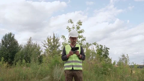 An electrical engineer in a white helmet inspects the poles and power lines. Stock Footage 165437740