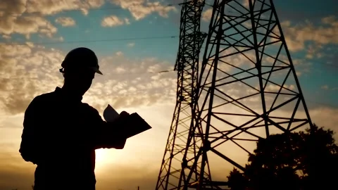 Electrical engineer worker in helmet silhouette working at sunset near the tower Video stock 133376042