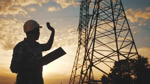 Electrical engineer worker in helmet silhouette working at sunset near the tower Stock Footage 135345817