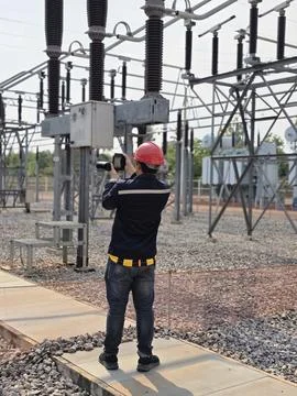 Electrical engineer worker wearing red safety helmet using thermal imaging .. Stock Photos