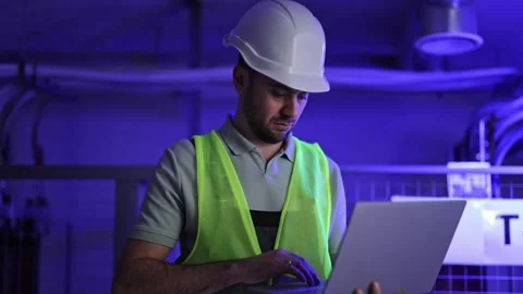 Electrical Engineer Working on Laptop in Control Room with Switchboard Stock-Footage 297842357