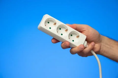 Electrical extension cord with multiple plug sockets held in hand by Caucasia Stock-Fotos