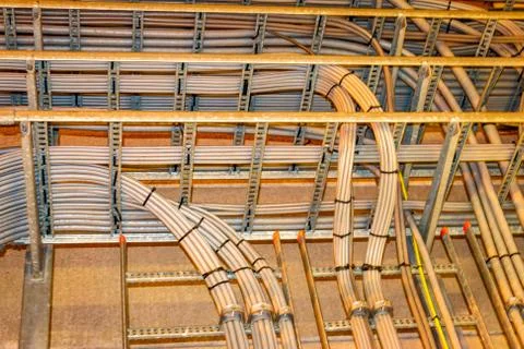Electrical grey cables mounted in a rack for power supply in a industrial area Stock Photos