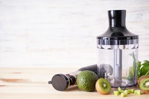 Electrical hand blender with sliced fruit on a wooden background, space for t Stock Photos