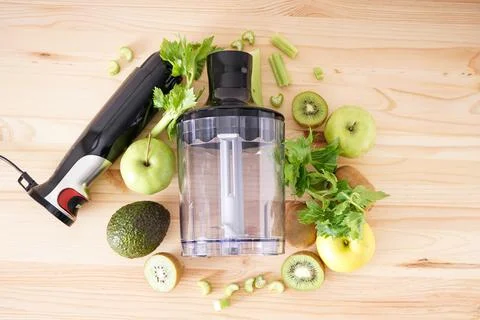 Electrical hand blender with sliced fruit on a wooden background, top view. Stock Photos