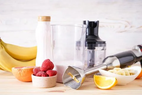 Electrical hand blender with sliced fruit on wooden background. Foto stock