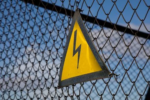 Electrical hazard sign on the grid Stock Photos