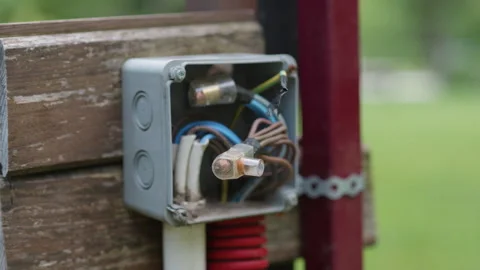 Electrical junction box with exposed wires and fuses mounted on wooden fence Stock Footage 340275537