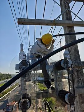 Electrical lineman installing twisted cable on concrete utility pole. Stock Photos