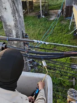 Electrical lineman technician using gas torch flame for heat shrinking insu.. Stock Photos