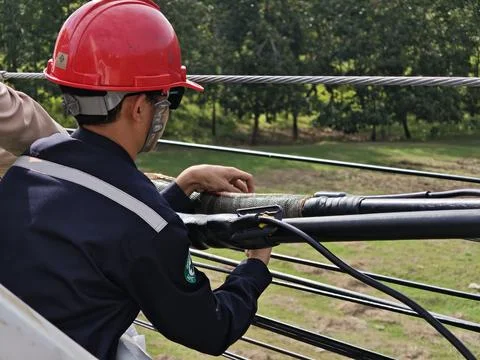 Electrical lineman technician working on twisted aerial bundle cable. Stock Photos