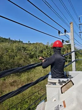 Electrical lineman technician working on twisted aerial bundle cable. Stock Photos