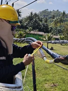 Electrical lineman using insulating tape on twisted aerial bundle cable. Stock Photos