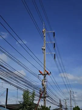 Electrical lineman worker climbing concrete utility pole using safety belt. Stock Photos