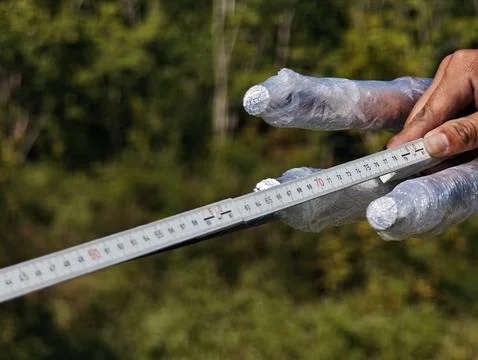 Electrical lineman worker hand measuring prepared twisted aluminum cable. Stock Photos