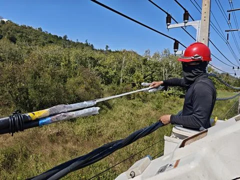 Electrical lineman worker measuring twisted aerial bundle cable length. Stock Photos