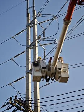 Electrical lineman worker team in mobile crane bucket lift replacing high volt. Stock Photos