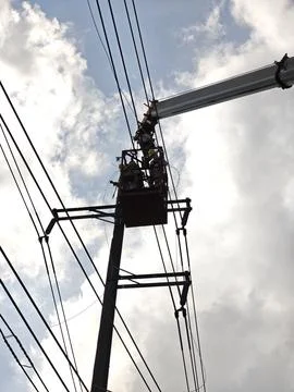 Electrical lineman worker team in mobile crane bucket lift replacing high volt. Stock Photos