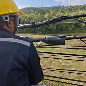 Electrical lineman worker using gas torch burner heating black heat shrink. Stock Photos