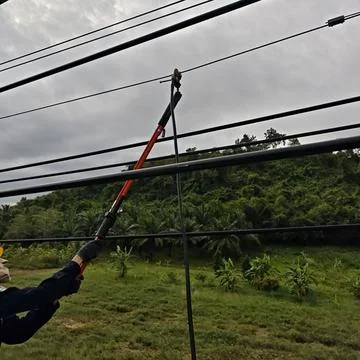 Electrical lineman worker using insulated telescopic hot stick to install. Stock Photos