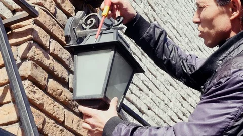 Electrical maintenance electrician change light bulb in house exterior wall lamp Vidéo 125843827