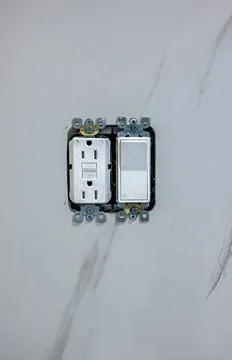 Electrical outlet and light switch installed in wall without cover plate. Close Stock Photos