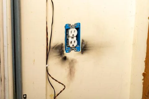 Electrical outlet with burn marks on wall from short circuit. Stock Photos