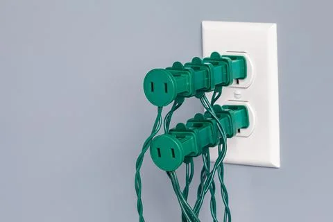 Electrical outlet overloaded with Christmas string lights. Stock Photos
