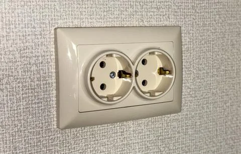 Electrical outlet on a wall featuring two socket openings Stock Photos