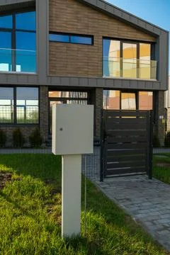 Electrical panel with meter installed on exterior wall of modern two-story to Photos