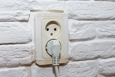 Electrical plug socket on white brick wall. Technology concept Stock Photos