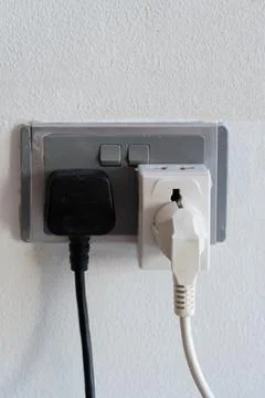 Electrical plugs inserted into wall sockets Stock Photos