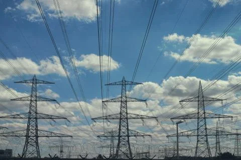 Electrical power lines as sun sets in background blue Foto stock