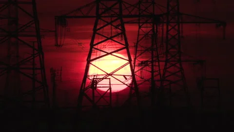 Electrical power transmission grid towers and lines with red sky and sun Stock Footage 149415899