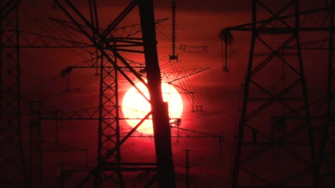 Electrical power transmission grid towers and lines with red sky and sun Stock Footage 149417857