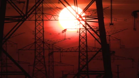 Electrical power transmission grid towers and lines with red sky and sun 库存影片 149420598