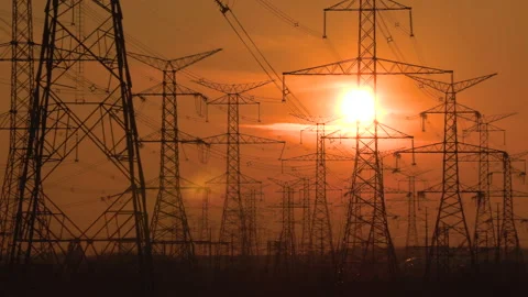 Electrical power transmission grid towers and lines with red sky and sun 库存影片 149424078