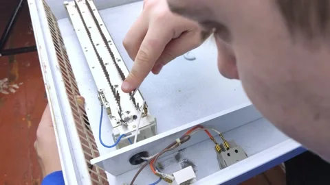 An electrical repairman repairs a convector. A close-up of an open heater and it Stock Footage 146840184