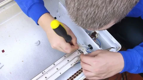 An electrical repairman repairs a convector. A close-up of an open heater and it Stock Footage 146840219