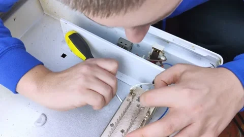 An electrical repairman repairs a convector. A close-up of an open heater and it Stock Footage 146840249