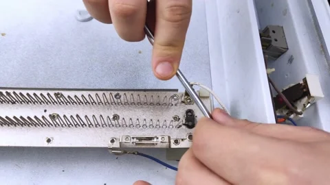 An electrical repairman repairs a convector. A close-up of an open heater and it Stock Footage 146840270