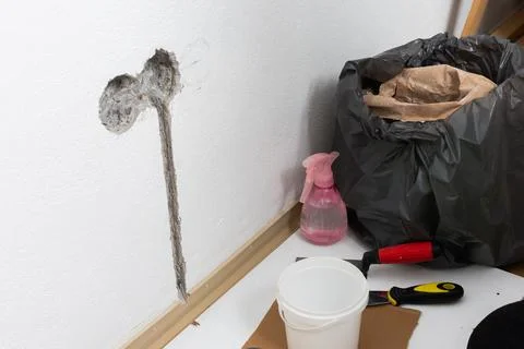 Electrical rough-in work is underway on a white apartment wall. An opening is Stock Photos
