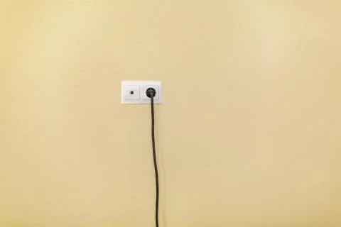 An electrical socket and TV outlet on wall with connected electrical black cable Stock Photos