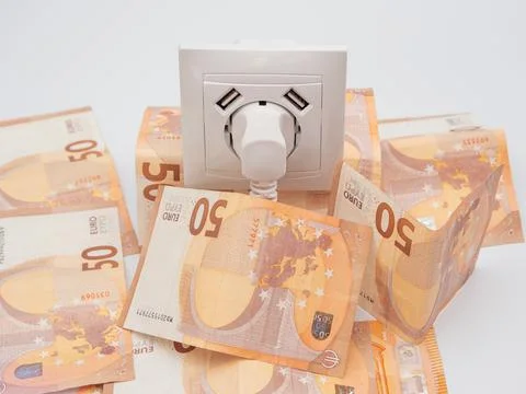 An electrical socket with a connected plug and euro banknotes around it. Stock Photos