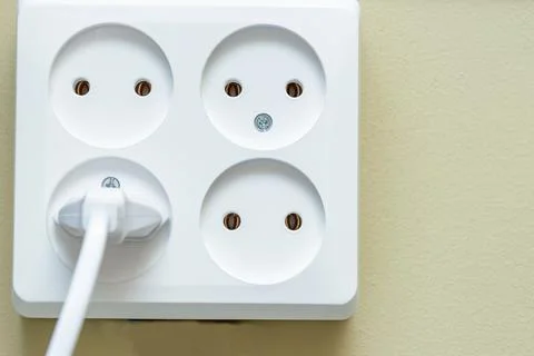 Electrical socket with four sockets. one of the outlets has an electric plug Stock Photos