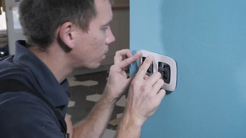 Electrical specialist fixes white switch frame on blue wall Stock Footage 106377058