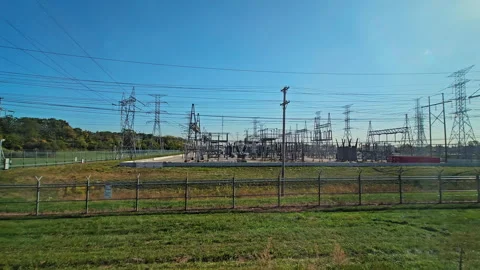 Electrical substation and power lines under a clear blue sky, surrounded by Stock Footage 301559143