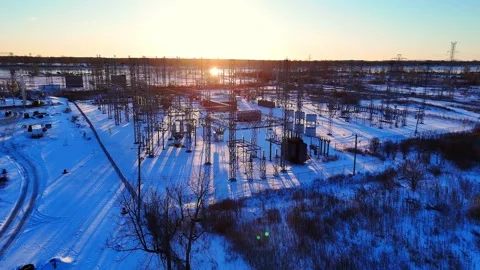 Electrical substation distributing power across snowy terrain at sunrise Vídeo Stock 333213775